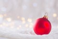 Red Christmas ball on white lace on light and warm bokeh background