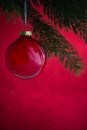 Red christmas ball on the xmas tree on red bokeh background. Merry christmas card. Royalty Free Stock Photo