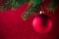 Red christmas ball on the xmas tree on red bokeh background. Merry christmas card. Royalty Free Stock Photo