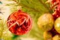 Red Christmas balloon on a Christmas tree against the background of shining garlands. Red ball surrounded by branches of the Chris Royalty Free Stock Photo