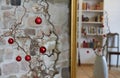 Red christmas balls at a branch in front of an unsharp stone wall in a loft apartment, unsharp reflections in a mirror with golden