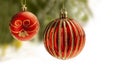 Red Christmas balls with gold decoration hanging from a Christmas tree with blurry background. Ball are partly isolated on white f Royalty Free Stock Photo