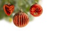 Red Christmas balls with gold decoration and a heart hanging from a Christmas tree with blurry background. Balls are partly isolat Royalty Free Stock Photo