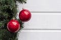 Red Christmas balls with green decor pine tree branch against white wooden wall, festive and winter background Royalty Free Stock Photo