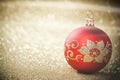 Red Christmas bauble on background of defocused golden lights. Royalty Free Stock Photo