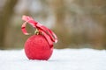 Red christmas bauble with bow outdoors in snow Royalty Free Stock Photo