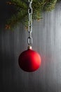 Red Christmas bauble on silver chain and spruce tree on steel metal background