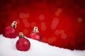 Red Christmas baubles on snow with a red background Royalty Free Stock Photo