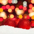 Red Christmas baubles in white snow against abstract bokeh light background Royalty Free Stock Photo