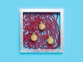 Red Christmas beads chain and three yellow gold balls in a silver frame on a blue color background. Abstract festive season art Royalty Free Stock Photo