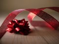 Red Christmas bow with ribbon on wooden background