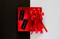 Red christmas box with red bow ribbon and black price tag on black and white background. Royalty Free Stock Photo