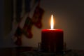 Red Christmas candle burning in the dark. Silhouettes of Christmas stockings in the background Royalty Free Stock Photo