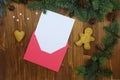 Red Christmas envelope with blank paper card. Fir branches, gingerbread man on a wooden background. Flat lay, top view. Letter to
