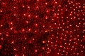 Red Christmas festive decorative background with tinsel, flashing lights. Wall illuminated by Christmas string rice lights bulbs.