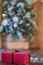 Red Christmas gift with black ribbon near Christmas tree on wooden table Royalty Free Stock Photo