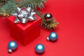 Red Christmas gift box with colored ribbon and Christmas balls on a red background. Royalty Free Stock Photo