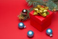 Red Christmas gift box with colored ribbon and Christmas balls on a red background. Royalty Free Stock Photo
