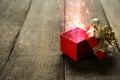 Red Christmas gift box with colorful magical lights on wooden desk Royalty Free Stock Photo