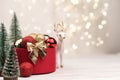 Red Christmas gift box with a gold bow on the background of bokeh, Christmas trees and deer Royalty Free Stock Photo