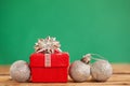 Red christmas gift box with green ribbon and three xmas balls on green background Royalty Free Stock Photo