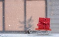 Red Christmas gift box on wooden sledges against the background of the Christmas window. Happy New Year and Merry Christmas