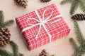 Red christmas gifts surrounded with pine cones, leaves and twine on a wooden table