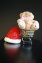Red Christmas hat, coins in miniature of trolley and cute teddy bear toy isolated on black dark background Royalty Free Stock Photo
