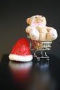 Red Christmas hat, coins in miniature of trolley and cute teddy bear toy isolated on black dark background Royalty Free Stock Photo