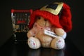 Red Christmas hat, coins in miniature of trolley and cute teddy bear toy isolated on black dark background Royalty Free Stock Photo