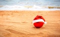 Red christmas ornament in santa hat on sand beach Royalty Free Stock Photo