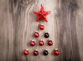 Red Christmas ornaments in the form of a Xmas tree on a rustic wooden background. Merry christmas card. Happy New Year. Top view Royalty Free Stock Photo