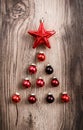 Red Christmas ornaments in the form of a Xmas tree on a rustic wooden background. Merry christmas card. Happy New Year. Top view Royalty Free Stock Photo