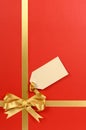 Red Christmas paper background, gold gift ribbon bow, blank gift tag vertical Royalty Free Stock Photo