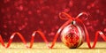 Red Christmas sphere with bow on glitter background Royalty Free Stock Photo