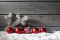 Red christmas spheres on pile of snow against wooden wall Royalty Free Stock Photo
