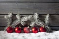 Red christmas spheres on pile of snow against wooden wall Royalty Free Stock Photo