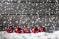 Red christmas spheres on pile of snow against wooden wall Royalty Free Stock Photo