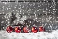 Red christmas spheres on pile of snow against wooden wall Royalty Free Stock Photo