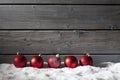 Red christmas spheres on pile of snow against wooden wall Royalty Free Stock Photo