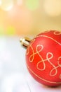 Red Christmas tree bauble on white wood background, colorful confetti lights in golden flare, copy space, greeting card Royalty Free Stock Photo