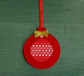 Red Christmas tree decoration made of felt with embroidered ornament on a green background Royalty Free Stock Photo