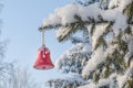 A red Christmas tree toy bell hangs on a snow-covered spruce branch in the forest after a heavy snowfall. Snow covering a pine Royalty Free Stock Photo