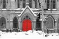 Red church door in snowy black and white winter street scene on 4th Avenue in the East Village of New York City Royalty Free Stock Photo