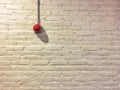 Red circle fire alarm on vintage white brick wall.
