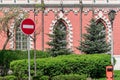 Red circular No Entry Stop sign with white horizontal line on brick wall and green trees background