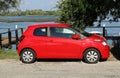 Red Citroen C1 parked by the sea. Side view.