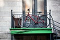 Red city bicycle parked in front of an old apartment door next to the staircase