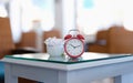 Red classic alarm clock standing on table in cafe closeup