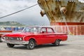 Red classic american car - Ford - in front of rusty ship in harbor of Santiago de Cuba